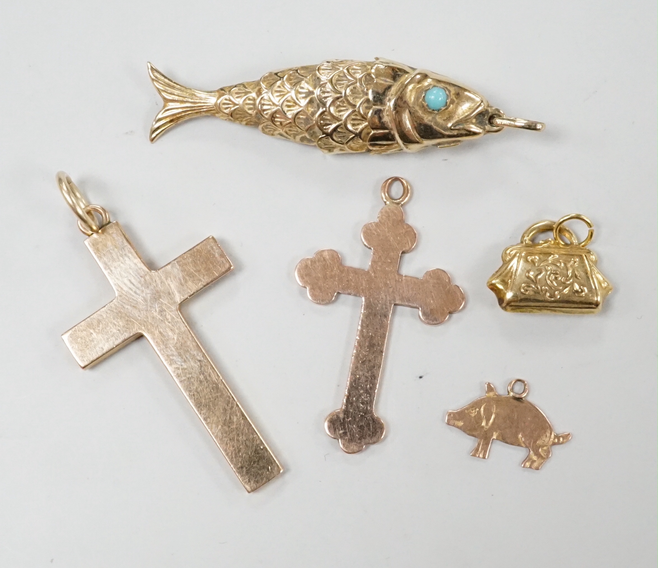 Two early 20th century 9ct gold cross pendants, three other 9ct charms including articulated fish, gross weight 11.8 grams.